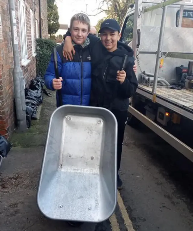 Two boys holding a wheelbarrow