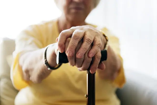 An elderly woman holding a walking stick