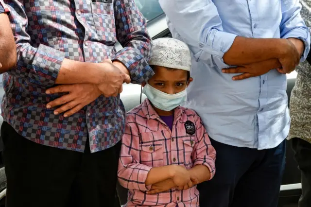 A boy wears a protective mask during Friday prayers outside a mosque in Bahrain