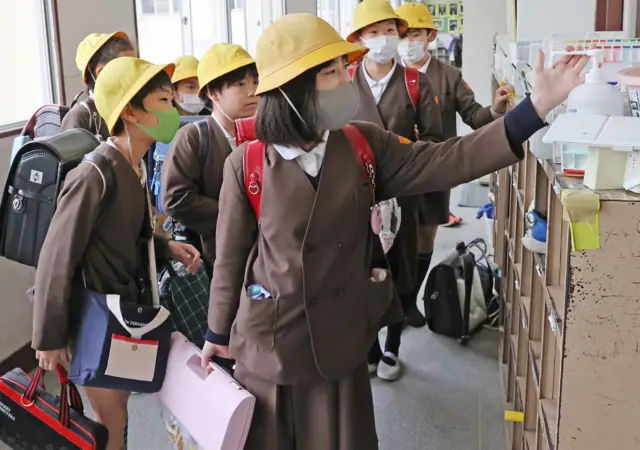 Elementary school children disinfect their hands before leaving school in Osaka