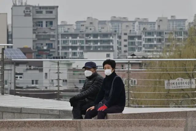 People wearing face masks take a rest at a park in Daegu on February 28, 2020