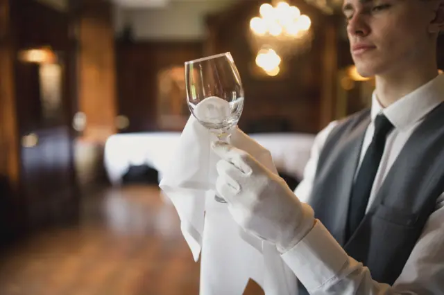 A hospitality worker polishing glasses