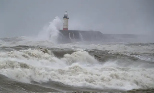 Waves crash against a lighthouse in East Sussex