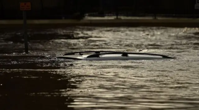 The roof of a submerged car is pictured in a flooded street in Mytholmroyd, northern England