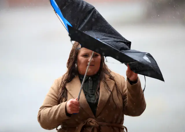 A woman's umbrella is blown inside out