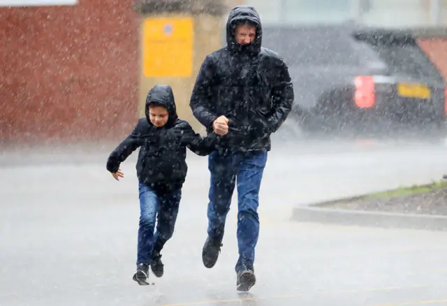 A man and a boy run through the rain for the Premier League match at Bramall Lane