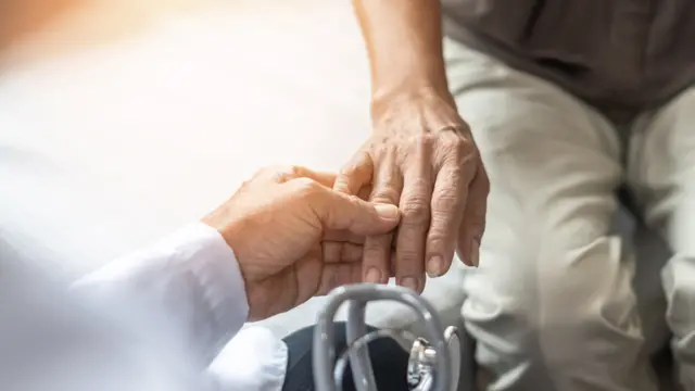 Stock image of a care worker holding the hand of a patient