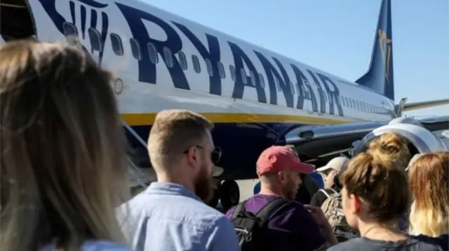 Passengers wait to board a Ryanair flight