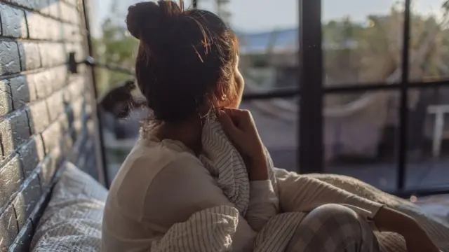 Woman sitting in bed looking out of a window