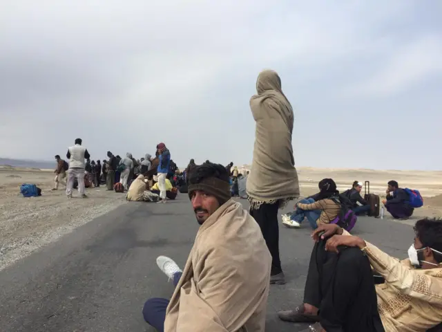 Pilgrims sit on a road on the Iran-Pakistan border