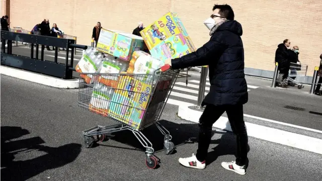 A man with a shopping trolley piled high with food