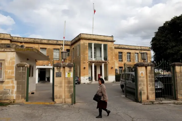 A woman walks past the entrance to Sir Paul Boffa Hospital