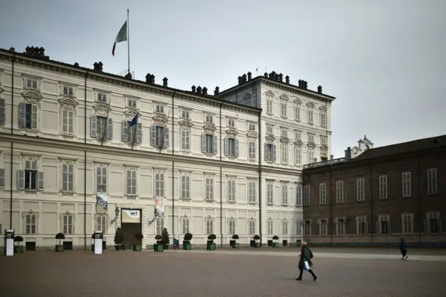 People walk by Palazzo Reale in Turin on March 9, 2020