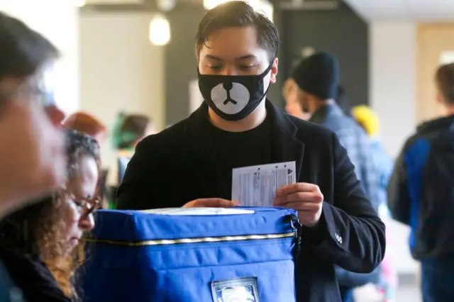 Matthew Guerrero, 22, of Des Moines, Washington wears a bear mask as he drops off his presidential primary mail-in ballot in person at King County Elections in Renton, Washington on March 10, 2020