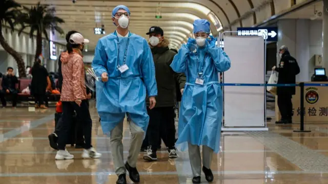 Workers in protective clothing at Beijing Capital Airport