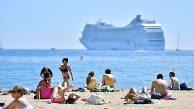 people on beach with cruise ship in background