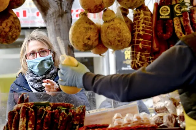 Customers at the Coldiretti farmers association market do their shopping wearing gloves and masks to protect themselves from the dangers of contagion from Coronavirus, in Naples, southern Italy,