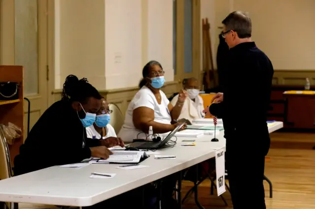 Election workers wear protective face masks as they check voters to get their to vote in the Michigan primary election at Central United Methodist Church in Detroit, Michigan, on March 10, 2020