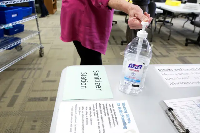 A woman uses hand sanitiser at a station set up for election workers sorting vote-by-mail ballots for the presidential primary at King County Elections in Renton, Washington on March 10, 2020