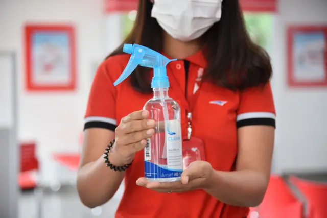 Postal worker holds a bottle of hand disinfectant