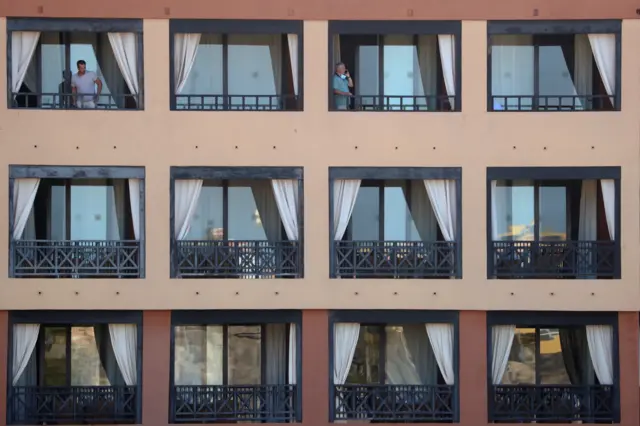 Guests stand in their terraces at the Costa Adeje Palace hotel on the Spanish Canary Island of Tenerife