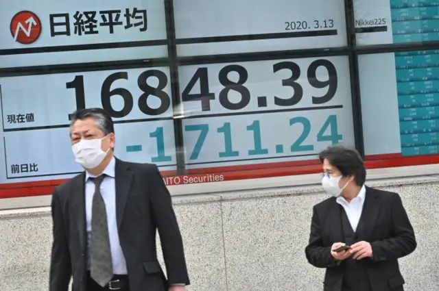 Men walk past stock market boards in Tokyo