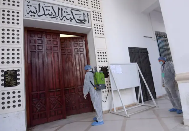 Health workers disinfect the entrance to the Ariana tribunal near the capital, Tunis, on 12 March.