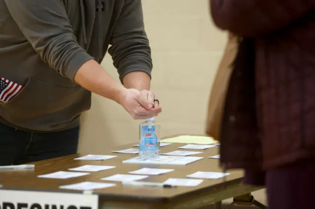 A Michigan voter uses hand sanitser