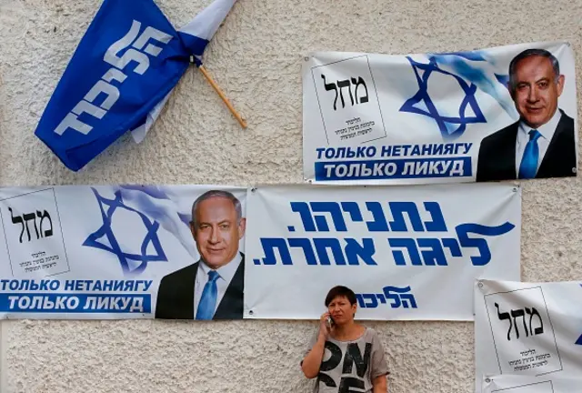 A woman talks on her mobile phone below banners for the Likud party