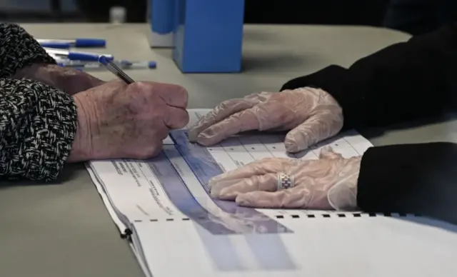 A French election official wears gloves during a local election