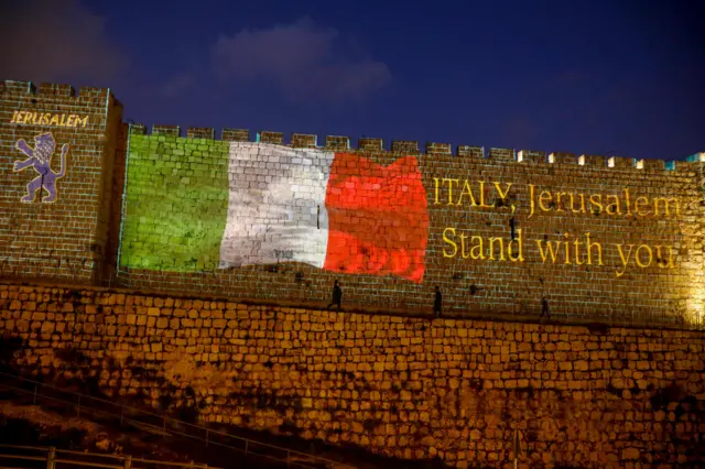 A picture taken on March 15, 2020 shows the Italian flag projected on the walls of the ramparts of Jerusalem"s Old City in a show of support for those suffering from coronavirus in Italy