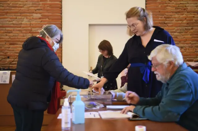 A voter wearing a protective mask casts her ballot at a polling station in Toulouse, southern France, on 15 March 2020