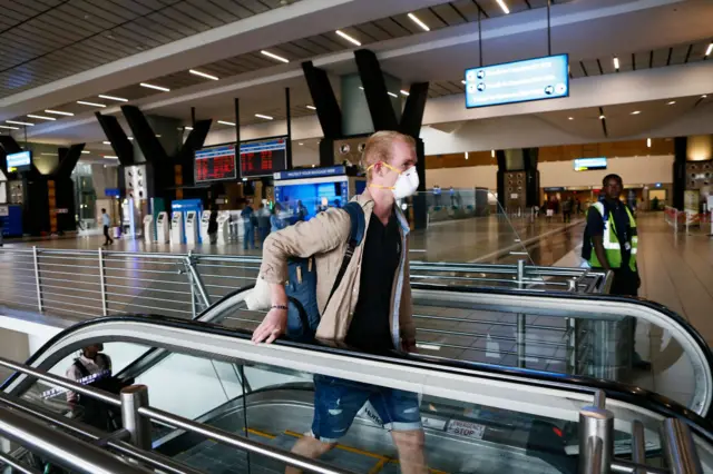 A traveller wearing a protective mask walks in OR Tambo International Airport, Johannesburg