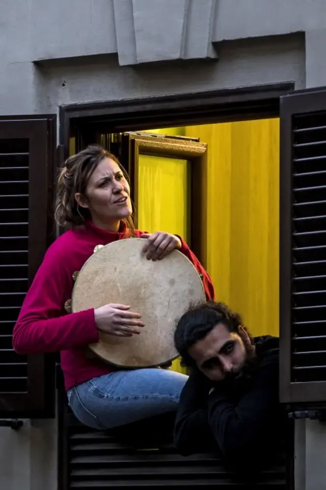 People sing from their home window during in the Pigneto district, in Rome, Italy, on 14 March 2020