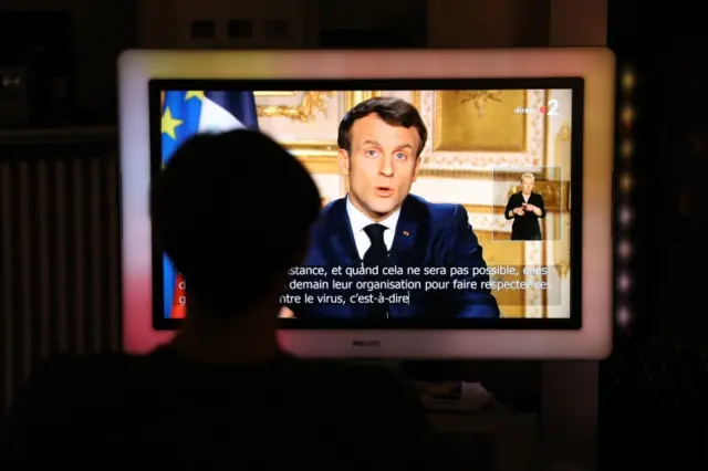 French President Emmanuel Macron is seen on a television screen as he speaks during a televised address to the nation on the outbreak of COVID-19, caused by the novel coronavirus, on March 16, 2020, in Paris.