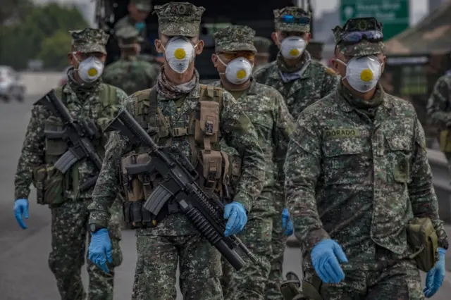 Filipino policemen wearing facemasks and gloves man a checkpoint as authorities begin implementing lockdown measures in Las Pinas, Metro Manila,