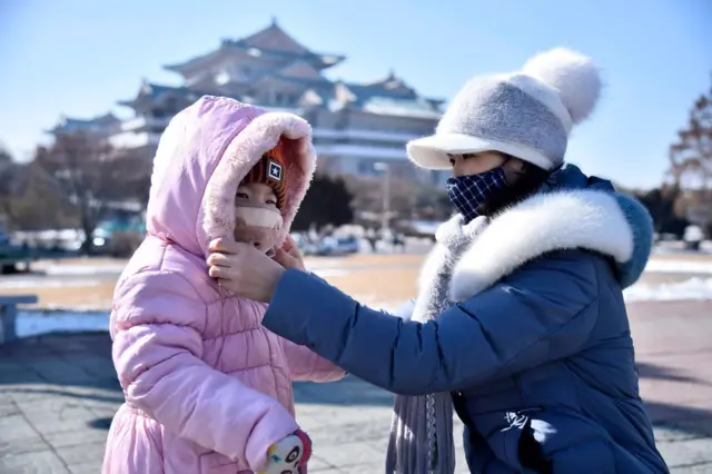 A woman helps her daughter seen wearing a face mask in Pyongyang.