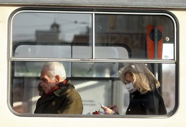 Woman wearing a medical mask is seen through the window of a bus