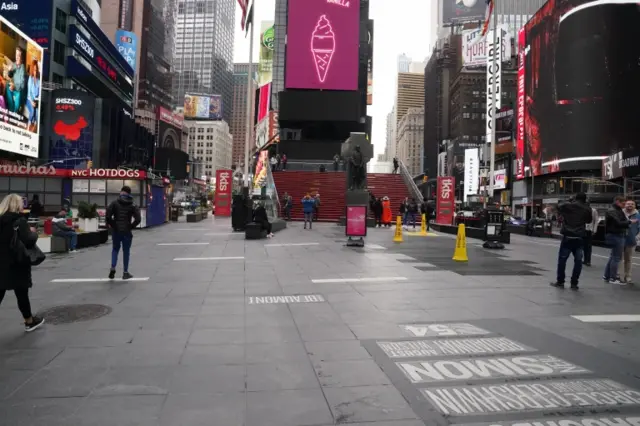 A few people walk in an unusually empty Times Square in New York City during the during the coronavirus outbreak