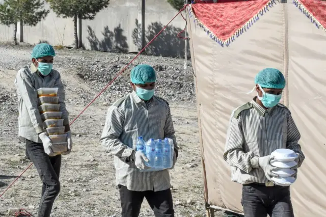 Officials bring supplies to the tent city at Taftan, where thousands have been held for several weeks