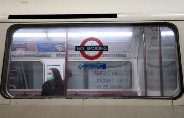 Woman on empty Tube carriage wearing mask