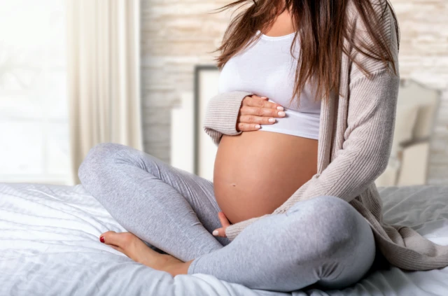 Stock image of a pregnant woman holding her stomach