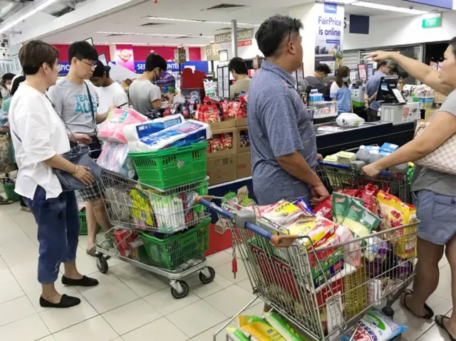 Singaporeans queue in a supermarket