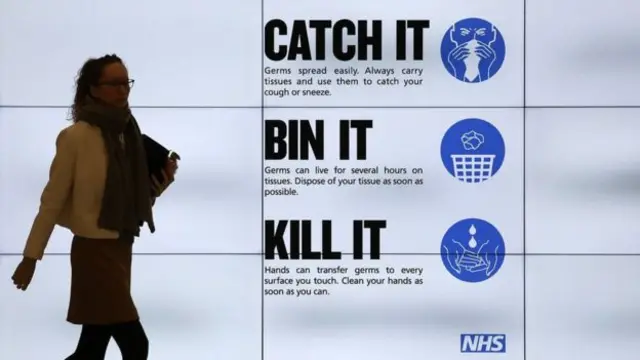 Woman walks past a sign reading "Catch it, bin it, kill it"