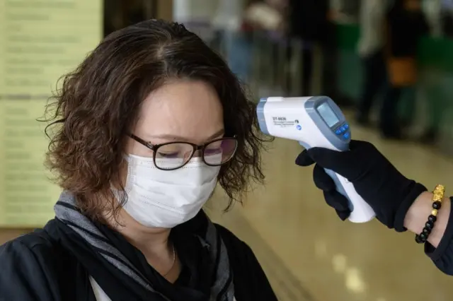 A woman wearing a mask has her temperature checked in Hong Kong