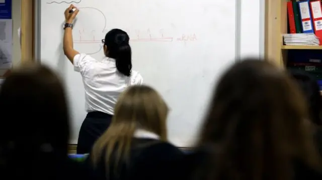 A teacher writes on a whiteboard