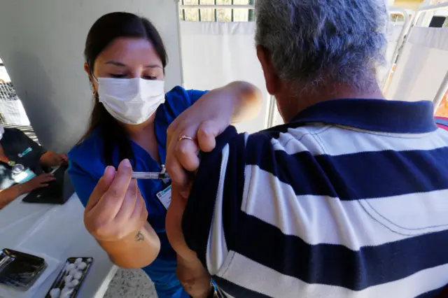 A nurse vaccinates a senior against influenza in Chile