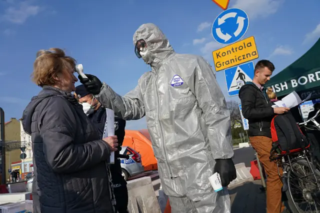 A Polish border guard takes the body temperature of a Polish woman