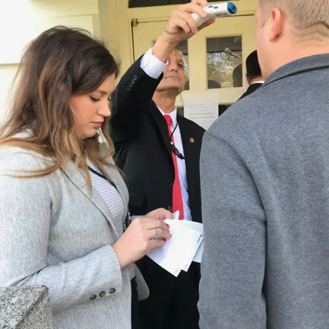 White House officials take the temperatures of reporters arriving for briefing (18 March)