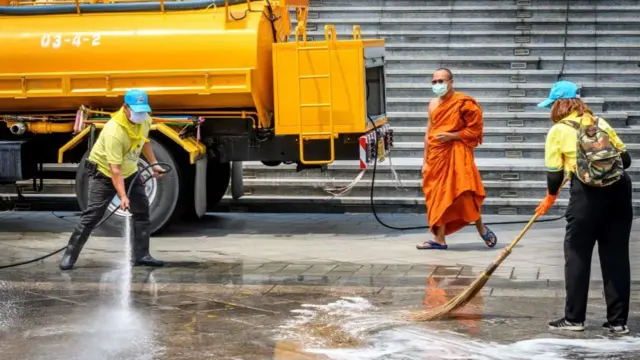 A Buddhist monk watches as volunteers use disinfectant to clean Wat Traimit temple in Bangkok on March 18, 2020